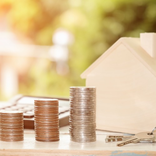 Un couple qui se tient la main, avec un agent immobilier, devant leur nouvelle maison, un exemple de la joie d'"Investir dans l’immobilier" et d'avoir sa propre maison.