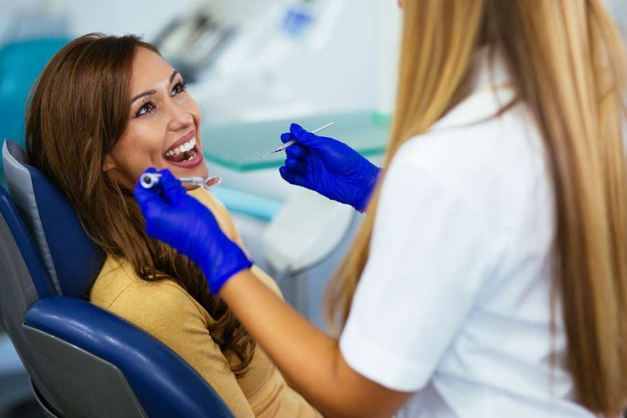 Une patiente souriante dans un fauteuil de dentiste lors d'une consultation pour le remboursement de vos soins dentaires.