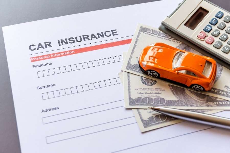 Un formulaire d'assurance auto avec une petite voiture miniature et une calculatrice.